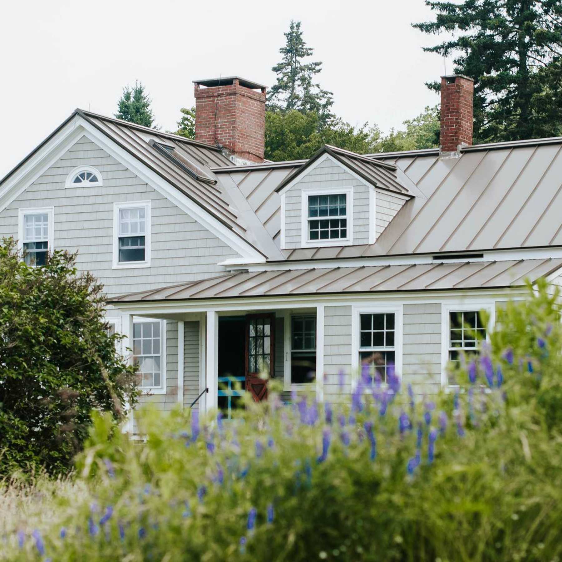 A large, grey home seen from the backyard